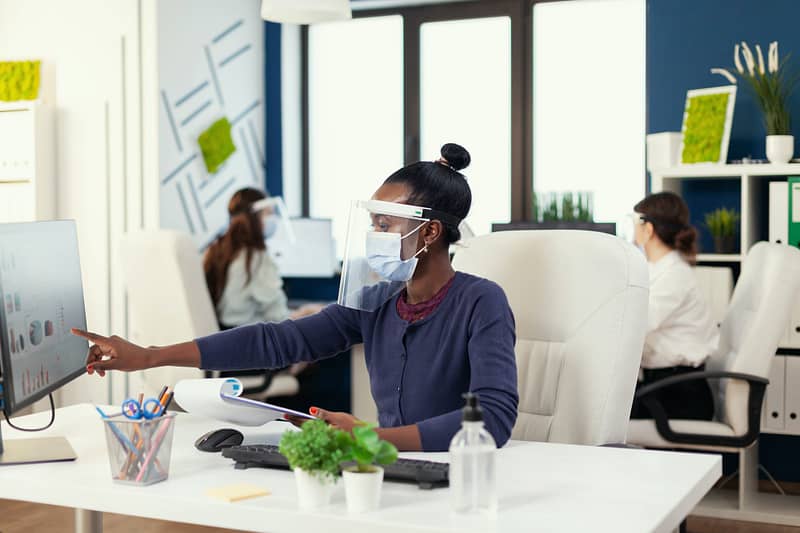 African marketing specialist at workplace wearing face mask